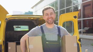 portret van een koerier Holding een twee pakjes, een geel auto in de achtergrond. levering van geneesmiddelen en producten video
