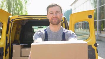 portret van een koerier Holding een perceel, een geel auto in de achtergrond. de koerier levert de pakket en hand- het naar de cliënt video