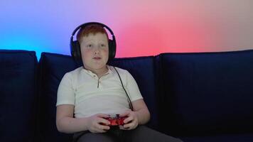 Gamer discussing tactics with teammates while talking into headset. Close up portrait of a little boy playing online computer game in the evening at home video