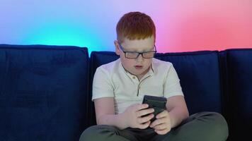 Boy uses old controller to play game. A boy plays old 8 bit game. Cozy room with warm and neon light video