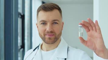 een dokter houdt een ampul met een vaccin in zijn hand. covid 19 vaccin video