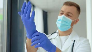 jong dokter in een beschermend masker zet Aan medisch handschoenen video
