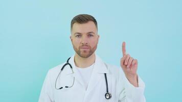 médico con estetoscopio en blanco Saco levanta su índice dedo arriba a cara nivel en un azul antecedentes video