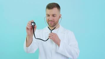 Masculin médecin avec une stéthoscope dans une blanc manteau sur une bleu Contexte video