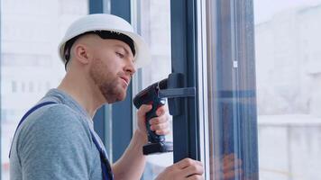 Meister im ein Helm und ein Schraubendreher installiert Fenster video