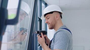 Window installer in a helmet and a screwdriver installs windows video