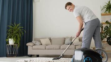 Senior woman vacuuming carpet at home. Housekeeping routine. Domestic hoover appliance cleaner video