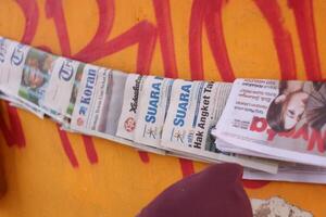 maglang, Indonesia.03 29 2024.noticias - doblada periódicos en frente de un naranja pared para venta. foto