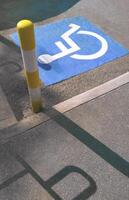 Light and shadow on surface of disabled wheelchair sign with yellow and white warning traffic post in public area photo