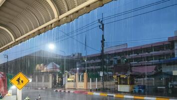 Raining on street in front of school in evening time, perspective side view from roadside area photo