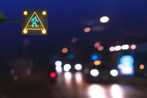 Illuminated electric traffic light pedestrian crossing sign with blurred night city street background photo