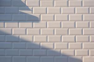 Sunlight and shadow on surface of white tile wall background photo