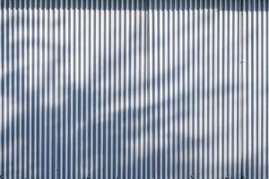 Corrugated zinc fence wall background with sunlight and leaves shadow on surface photo