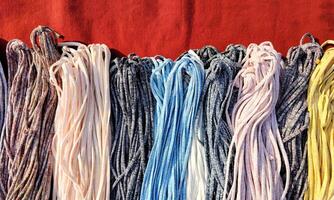 Pile of many bunch of colorful cloth ropes for sale on red cloth in outdoor flea market, top view with copy space photo