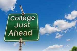 Green road with the words College Just Ahead against blue sky and clouds background. photo