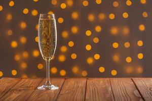 Glasses with champagne on a wooden background against a bokeh background of lights photo