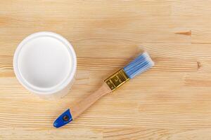 white paint with a brush on a wooden background with texture photo