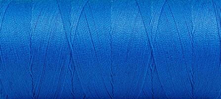 Texture of threads in a spool of blue color on a white background photo