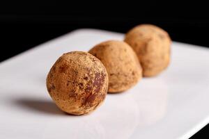 Beautiful candy truffle on a white plate on a black background photo