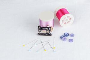 todavía vida de un madeja de hilo para de coser, agujas, botones, de coser máquina en un blanco antecedentes foto