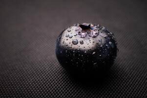 One blueberry covered with water drops on black background. Very detailed macro shoot with copy space photo