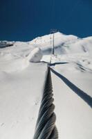 Steel cable of a cable car close-up. Rope texture. The path of the cable cabin against the backdrop of snow-capped mountains photo