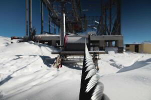 A cable car station under construction high in the mountains in winter. Focus on a close-up of a thick cable car cable covered with snow photo