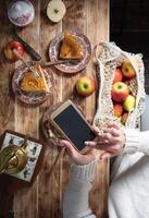 blogger photographing Thanksgiving apple pie table setting with mobile phone photo