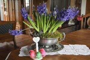 large pewter vase with purple hyacinths on a table in the hall in a rustic style photo