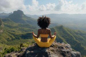 A black woman with natural curly hair meditating on the top of the mountain photo