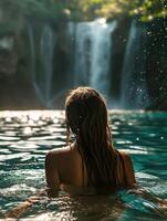 Photo of a woman swimming in a huge lake with a waterfall in the background