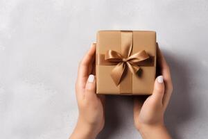 Female hands holding a gift box on a light background, top view photo