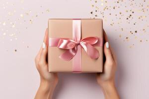 Female hands holding a gift box on a light background, top view photo