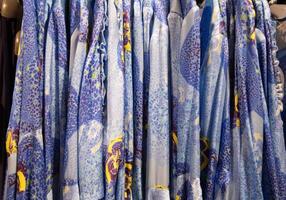 blue with yellow flowers summer blouses on a hanger in the store, bright clothes photo