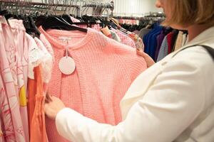 girl millennial in the store chooses on a hanger pink blouse, fashion clothes photo