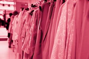 summer blouses on a hanger in the store, concept color of the year 2023 Magenta photo