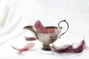 vintage silver gravy boat on a white background with purple feathers,still life photo