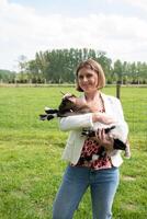 Young woman plays with goat kids, feeding them, sun shining, countryside photo