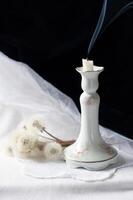 Still life with an antique porcelain candlestick and smoke from an extinguished candle,mood of loss and condolences photo