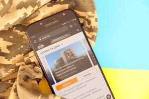 KYIV, UKRAINE - 4 MAY, 2023 Unian ukrainian news portal on smartphone screen with ukrainian flag and camouflage fabric photo