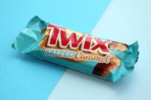 TERNOPIL, UKRAINE - JULY 7, 2023 Twix salted caramel blue wrapper on wooden background. Twix is a chocolate bar made by Mars Inc consisting of biscuit applied with caramel photo