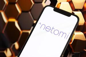 KYIV, UKRAINE - MARCH 17, 2024 Netomi logo on iPhone display screen with background of artificial intelligence futuristic image photo