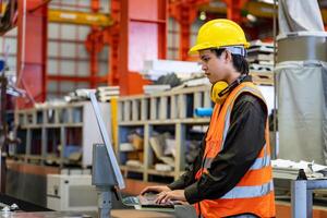 Ingenieria técnico trabajador es operando el máquina dentro fábrica utilizando toque pantalla computadora monitor a mando el orden para línea producción y acero industria foto