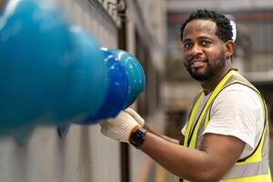 African American worker is hanging his safety helmet on the rack inside the heavy industrial factory for protection and accident prevention photo