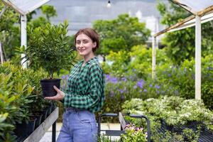 Young caucasian customer is choosing exotic plant from the local garden center nursery with shopping cart full of summer plant for weekend gardening and outdoor concept photo