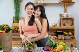 Asian couple of same sex marriage hugging each other while cooking healthy salad together in kitchen during pride month to promote equality and differences of homosexual and discrimination photo