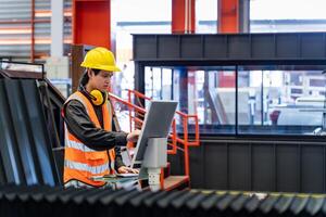 Ingenieria técnico trabajador es operando el máquina dentro fábrica utilizando toque pantalla computadora monitor a mando el orden para línea producción y acero industria foto