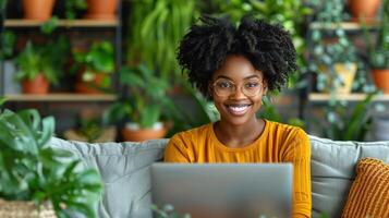 A woman is seated on a couch, working on a laptop photo