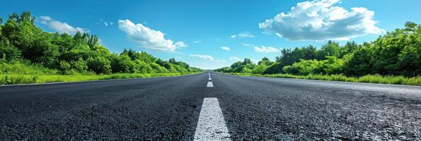 A deserted road cutting through a landscape of dense trees and lush grass photo