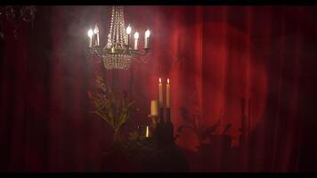 lustre com cristais contra uma vermelho cortina, decorado etapa video